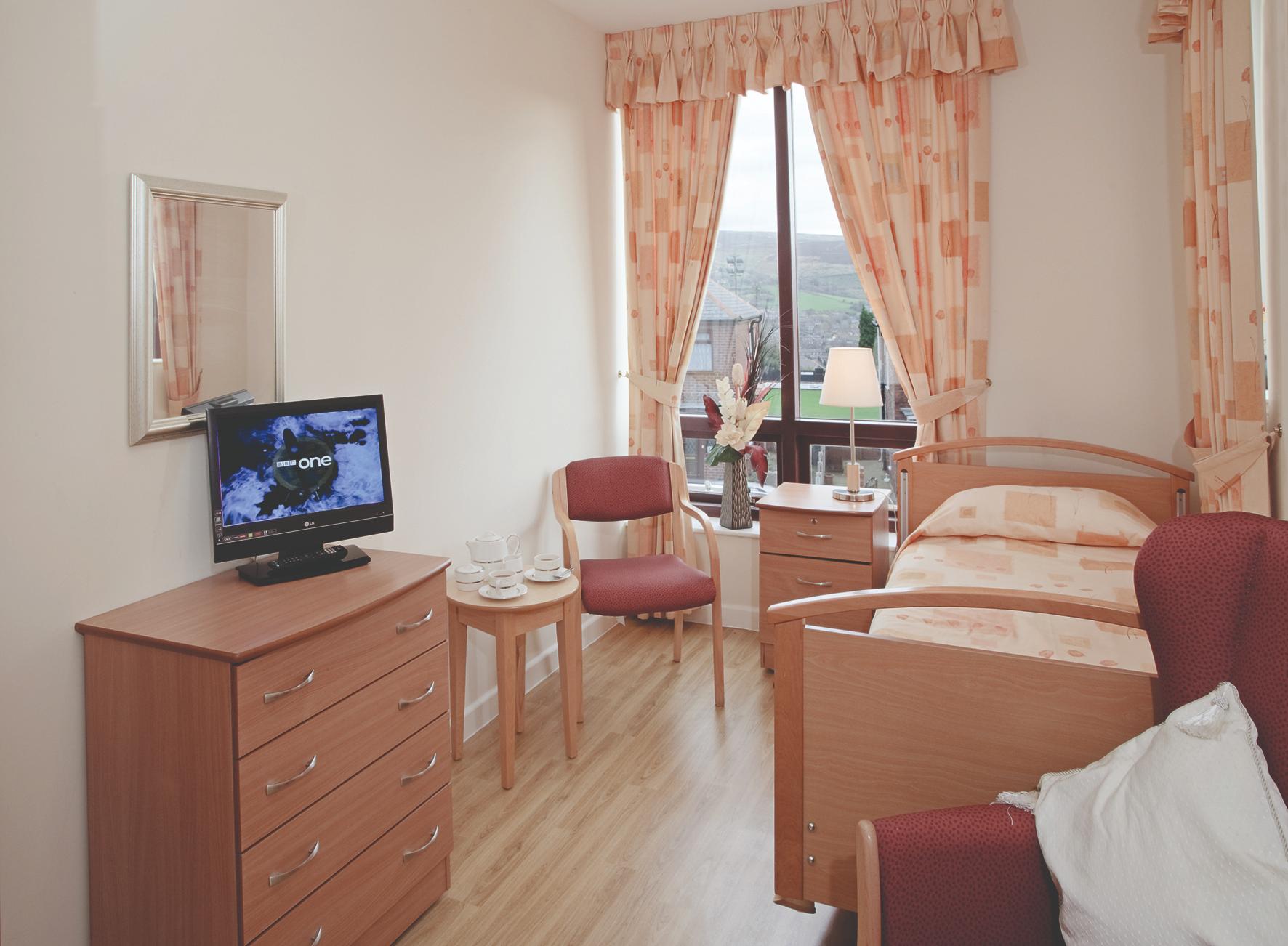 decorated care home bedroom with pink textiles and television